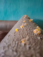 Close Up of Damaged Grey Surface with Yellow Accents Against a Teal Background