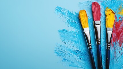 Fototapeta premium Paintbrushes with colorful paint on a blue background. Concept of art, painting, and creativity.