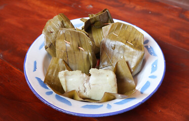 Meniran is a snack made from rice cooked with coconut milk and wrapped in banana leaves. This classic snack is savory and filling. Served on a vintage plate on the table. Traditional javanesse snack