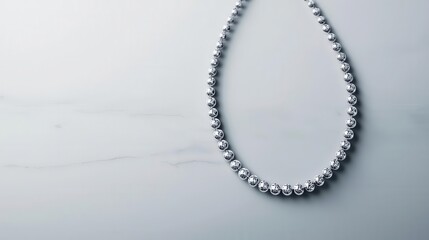 Minimalist diamond tennis necklace arranged in a loose oval, isolated on a clean white marble background