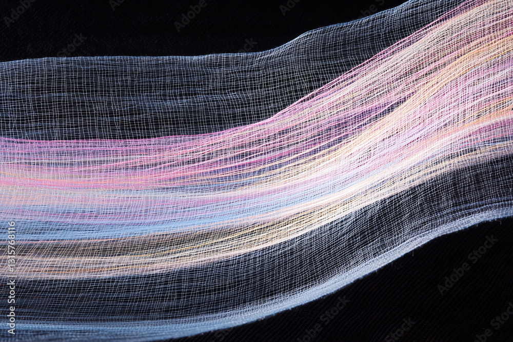Poster close up of colorful woven fabric highlights intricate texture and flowing pattern against dark back