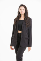 Portrait of asian beautiful woman curly long hair, wearing black suit, black long pants, model girl positive attractive confident charming, standing pose look at camera on white background in studio.