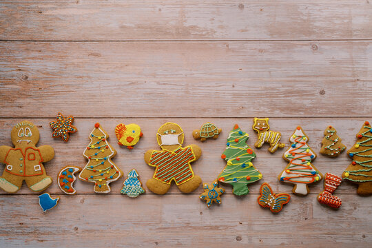 Colorful Christmas gingerbread cookies lie in a row on a light wooden background - Powered by Adobe