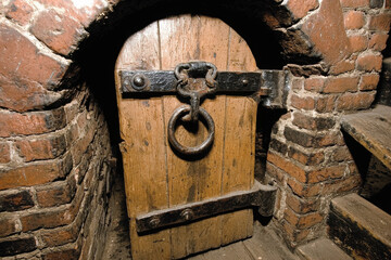 Old Rustic Wooden Door with Heavy Chain and Lock in a Brick Wall Basement