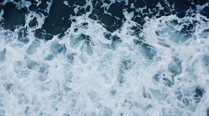 Fototapeta premium Aerial view of ocean waves crashing, creating white foam and deep blue water patterns in dynamic and textured seascape. swirling motion of sea conveys energy and natural beauty