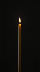 Lit Candle Burning Bright Against a Dark Black Background Creating Soft Light