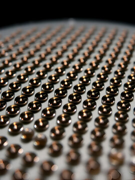 Tiny microlenses arranged in a two-dimensional array on a silicon wafer surface, each lens exhibiting diffraction patterns under various illumination conditions , optics, nanotechnology