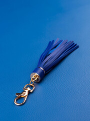 Close up of blue leather tassel keychain on blue background