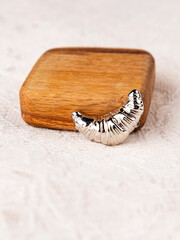 Close up of silver croissant brooch on white background