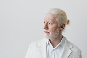 Obraz premium Portrait of a thoughtful man with light hair and beard against a minimalistic white background, exuding a calm and reflective demeanor