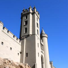 Obraz premium Stone Fortress: A majestic stone castle with towering turrets and intricate details stands against a clear blue sky. Its ancient walls whisper tales of bygone eras and forgotten heroes.