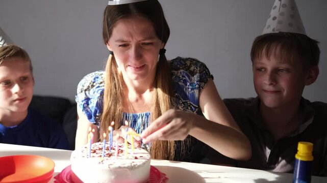 Happy birthday. Happy family celebrating birthday together. Single mother and her children having fun at home together. Candles on cake. Part of series