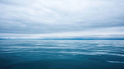 Obraz premium Expansive Tranquil Seascape with Calm Water and Overcast Gray Sky Reflecting on Gentle Ocean Waves