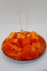 Fresh ripe papaya slices served on a golden plate with a plastic fork. Sweet and juicy tropical fruit, rich in vitamins, perfect for a healthy snack or dessert. Vibrant orange color enhances its appea