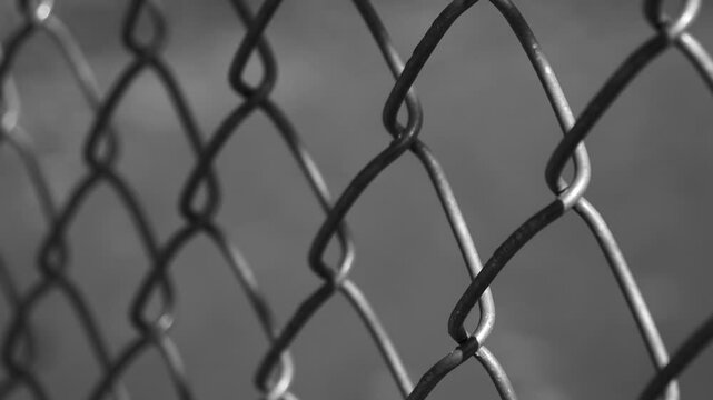 Black and white high contrast slow motion of chain link fence close up with blurred background