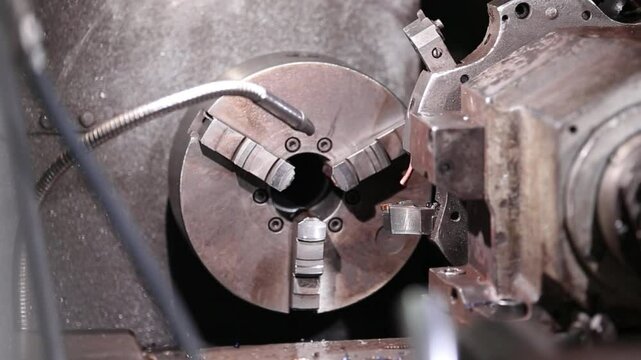 A factory worker makes a part at a lathe