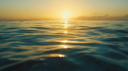 Obraz premium Golden sunset reflecting on calm ocean waves.