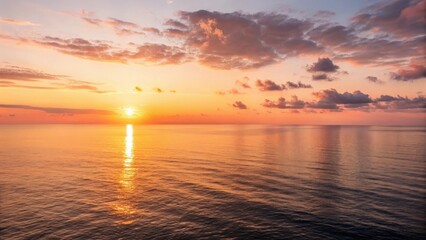 Obraz premium Sunrise Over Ocean serenity atmosphere Vibrant sunset over calm ocean waters, reflecting golden hues and fluffy clouds.