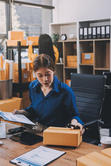 Asian SME business women use laptop computer checking customer order online shipping boxes at home....