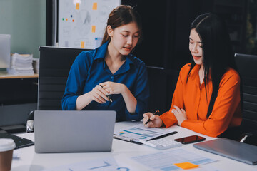 Entrepreneur Asian businessman and businesswoman discussing new business project in tablet in modern Meeting In Modern Office, Asian business casual concept.