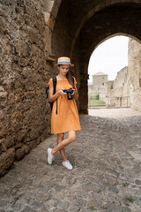 tourist with camera taking pictures in medieval fortress, Ukraine. Young photographer woman