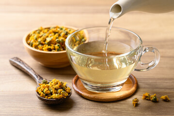 Chrysanthemum tea in teapot pouring into cup glass, Healthy herbal drink