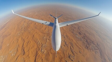 High angle view of a white unmanned aerial vehicle (UAV) flying over a vast, arid desert landscape under a clear blue sky.