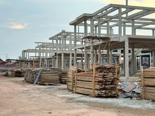 Reinforced steel and concrete building under construction, lumber pilling up.