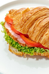 croissant with greens, ham and tomato