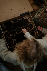 Children planting seeds together in biodegradable pots outdoors.