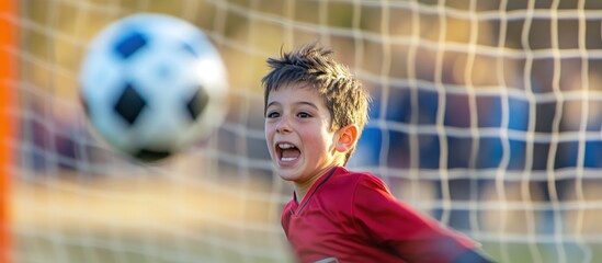 Excited boy watches soccer ball nearing goal.