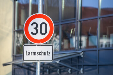 Verkehrsschild Tempo 30 Lärmschutz in Hauptstraße vor Glasfassade mit Vordach  mit Spiegelung Fachwerkhaus in Wohngebiet in Neckartenzlingen