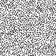 Abstract black and white Memphis pattern featuring small dots and dash shapes isolated on a white background for graphic design.