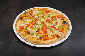 A pizza with vegetables on it is sitting on a white plate