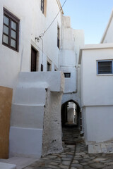 Narrow alley with tunnel and with whitewashed walls and stone pavement leading to a courtyard in the Greek Islands, Greece
