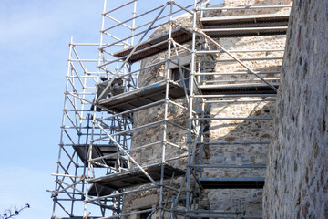 Scaffolding covering stone wall of building under renovation
