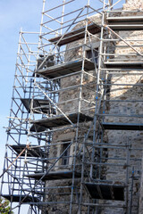 Scaffolding covering stone wall of building under renovation