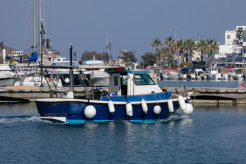 Fishing boat leaving harbor in lipsi, greece, on a sunny day