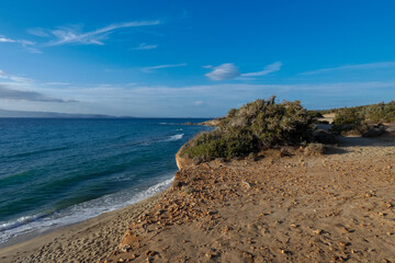 Sun shining over a secluded beach with vegetation and cliffs at sunset