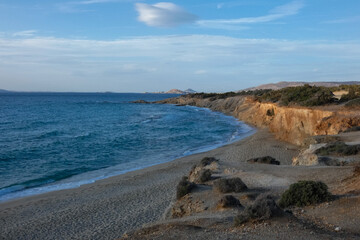 Sun shining over a secluded beach with vegetation and cliffs at sunset