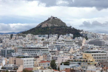 Athens cityscape expanding towards mountains under cloudy sky