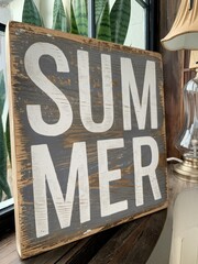 "Weathered Wooden Summer Sign with Lush Green Plants and Vintage Decor in Background"