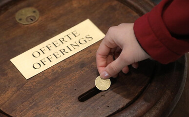 hand of young girl putting european money coin into the offering box