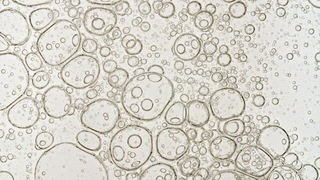 Transparent cosmetic gel fluid with molecule bubbles oil spreading on a white background. Macro Shot of Natural Organic Cosmetics, Medicine. Production Close-up. Slow Motion. High quality 4k footage