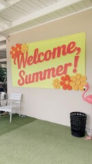 "Cheerful 'Welcome, Summer!' Sign on Beige Wall with Floral Decor and Green Grass Flooring"