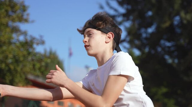 Slow motion of a teenage boy playing tennis in summer, vol&egrave;e at net.