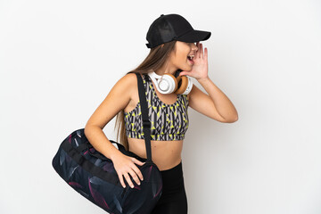 Young sport woman with sport bag isolated on white background shouting with mouth wide open to the...