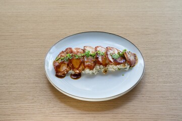 A plate of meat with sauce and vegetables on a wooden table