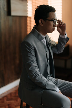A young man sitting holding an eyeglass