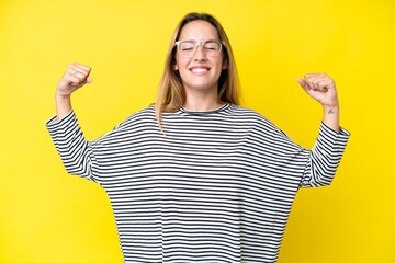 Young caucasian woman isolated on yellow background doing strong gesture